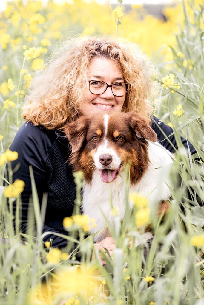 Frau und Australian Shepherd sitzen im Raps