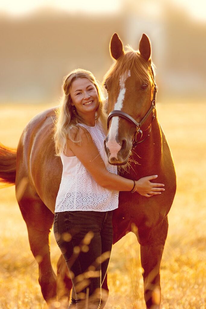 Frau und fuchsfarbenes Pferd im Gegenlicht
