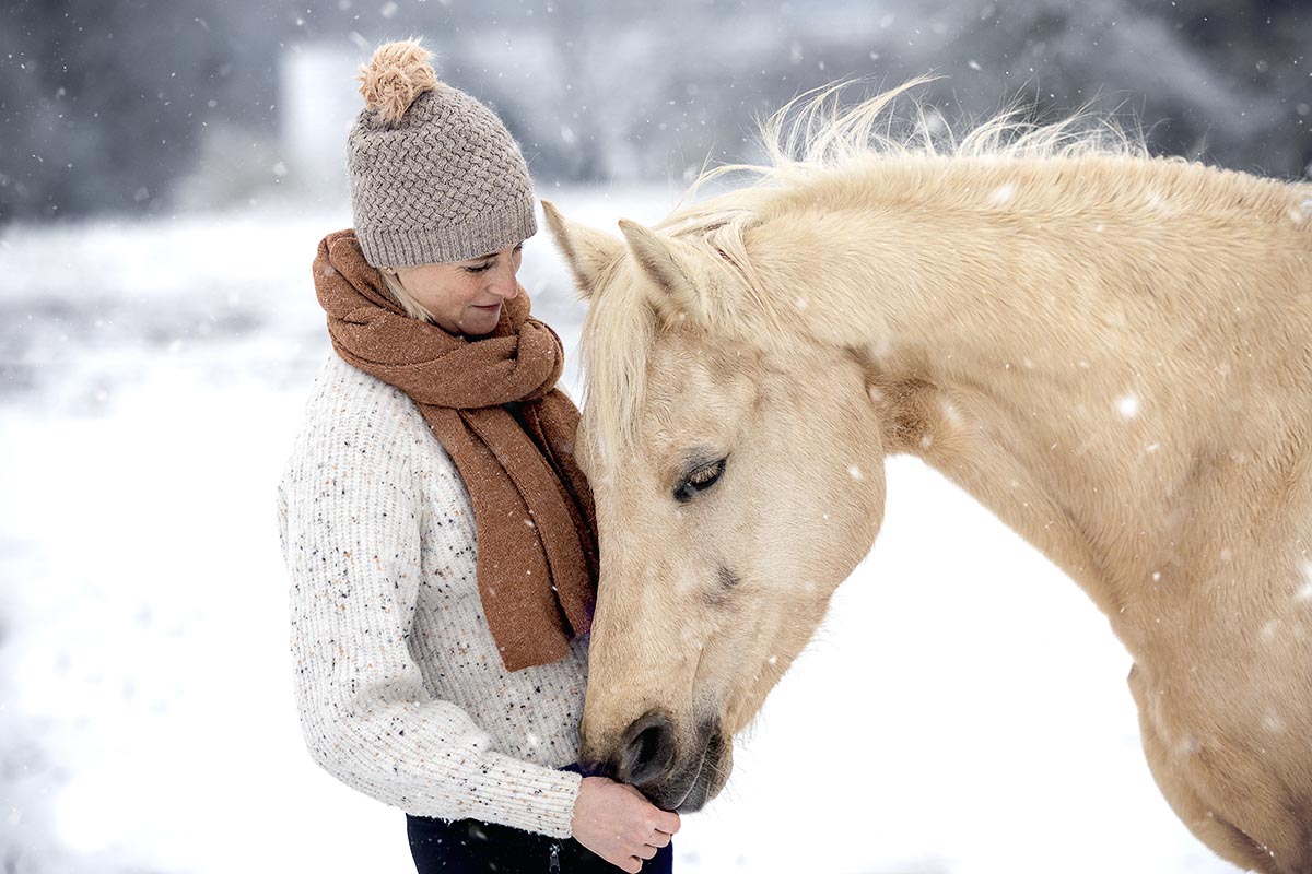 Frau und helles Pferd im Schnee
